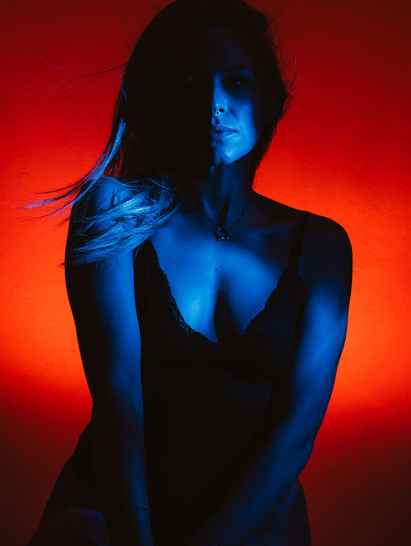 High-contrast self portrait with complementary red and blue flash lighting and strong color separation