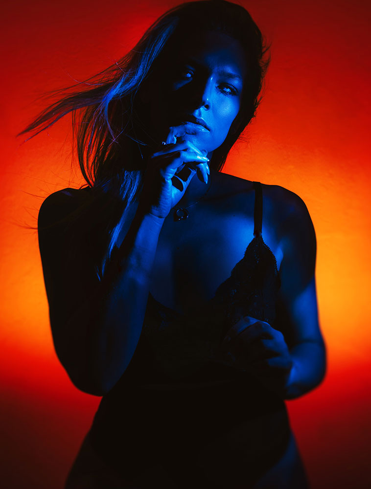 Self portrait in red and blue color filter lighting with off-camera flash, wind-blown hair and sculpted shadows