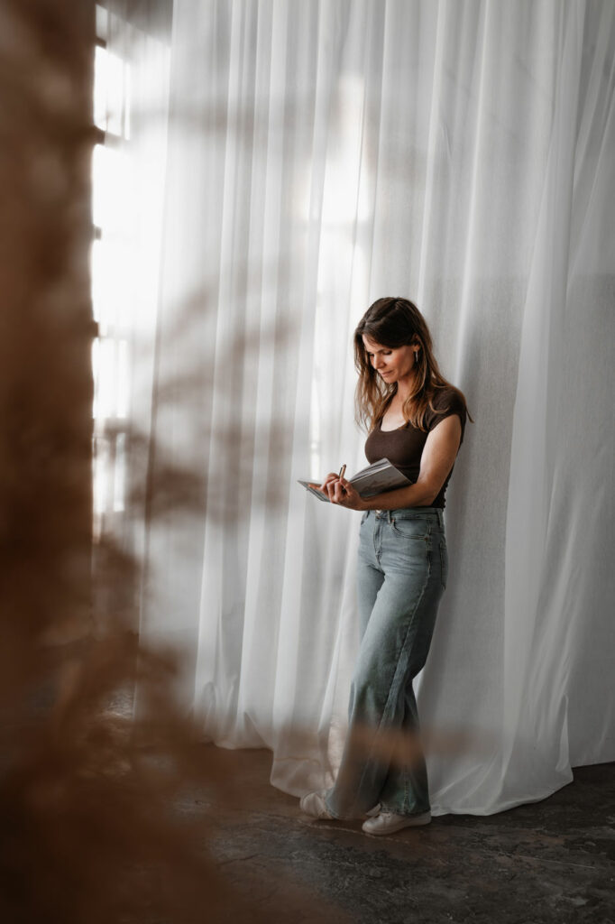 Personal Branding Portrait einer Frau in natürlichem Licht stehend mit Notizbuch