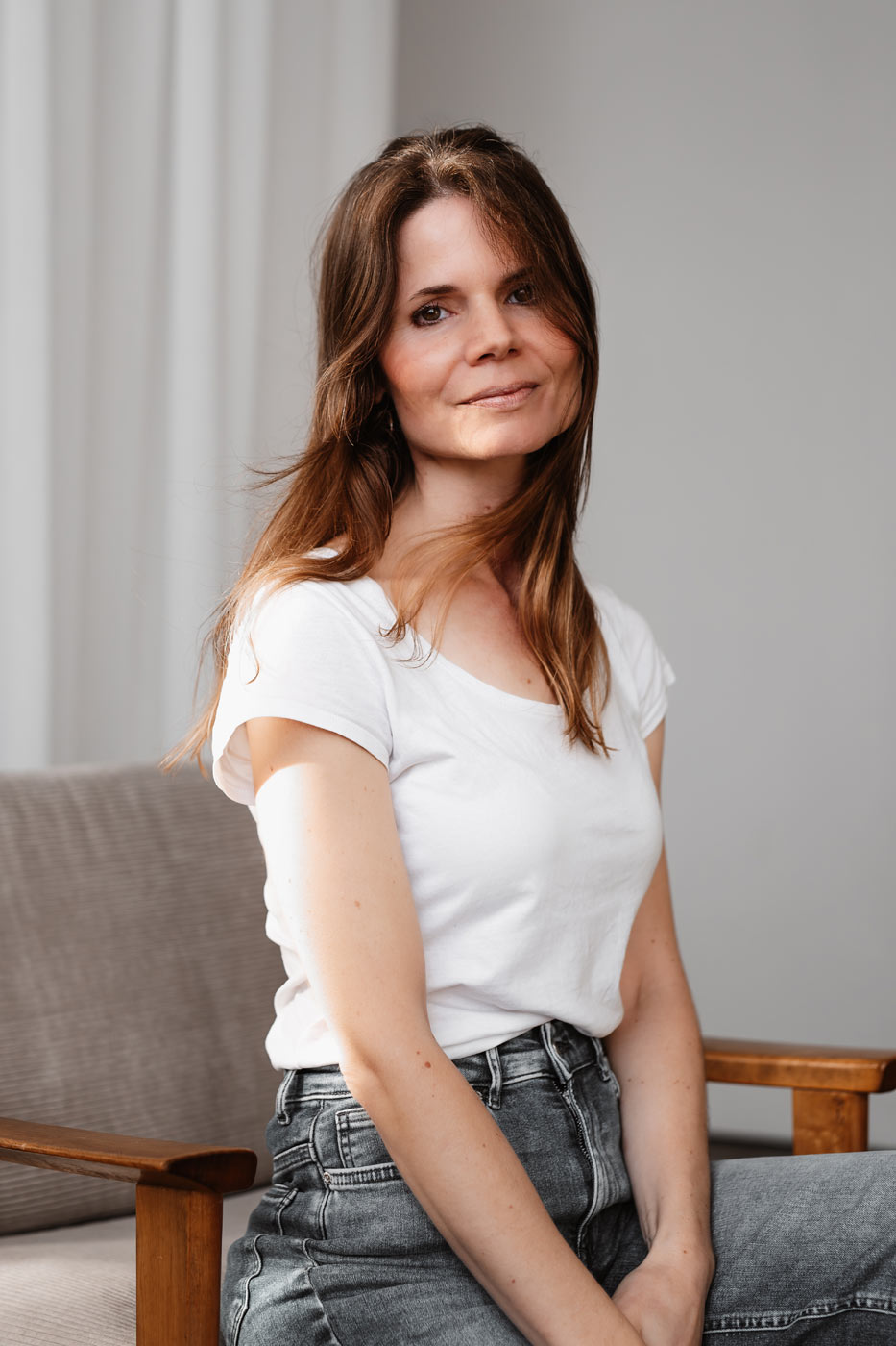 Personal Branding Portrait einer Frau in natürlichem Licht sitzend auf einem Holzstuhl